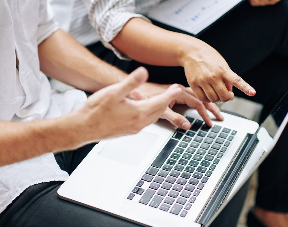 Close-up image of business people discussing report and analyzing data on laptop screen